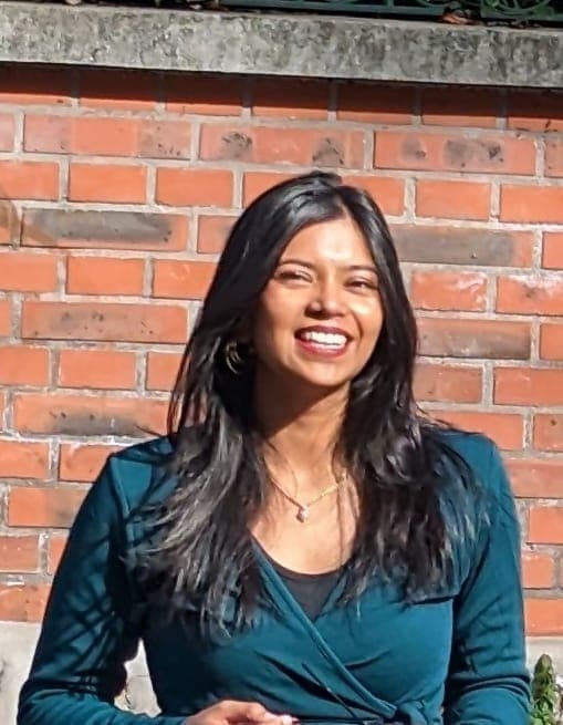 Satavisha Mitra smiling in front of a brick wall